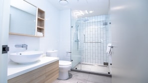 Une salle de bain moderne avec un lavabo blanc, des toilettes et une douche à parois de verre.