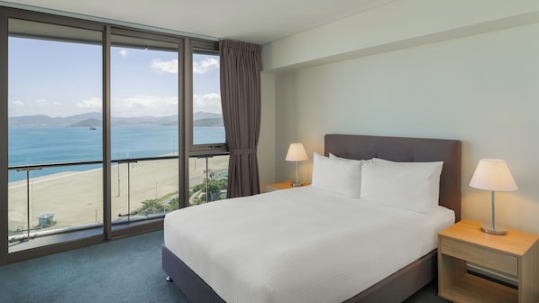 Une chambre d’hôtel dotée d’une grande fenêtre donnant sur la plage et l’océan.