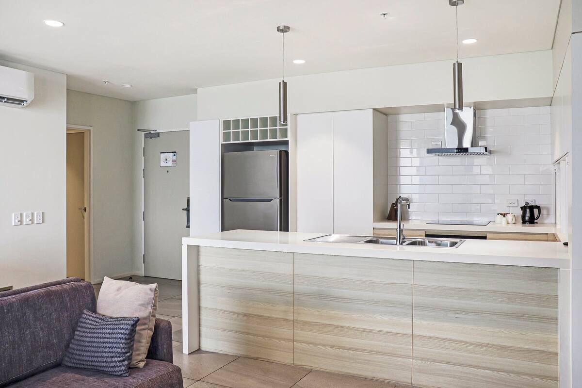 A modern kitchen with a stainless steel refrigerator, a built-in oven, and a sleek faucet.