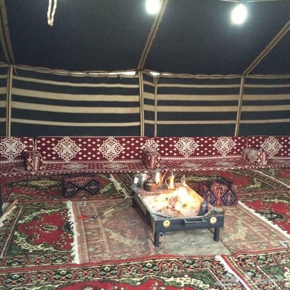 A tent with a patterned sofa and a central fire pit.