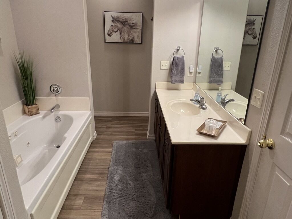 A bathroom with a bathtub, a sink, a mirror, and a towel rack.