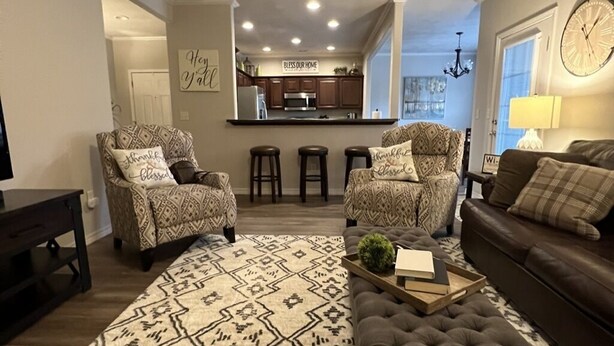 A living room with patterned armchairs, a brown sofa, and a rug with a geometric design.