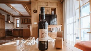 Une bouteille de vin Cape Rook Pinot sur une table en bois, dans une cuisine dotée de meubles en bois et d’une grande fenêtre.