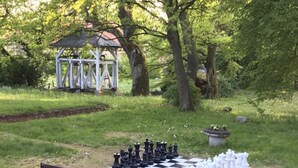 Un jeu d’échecs installé à l’extérieur, avec un kiosque en arrière-plan.