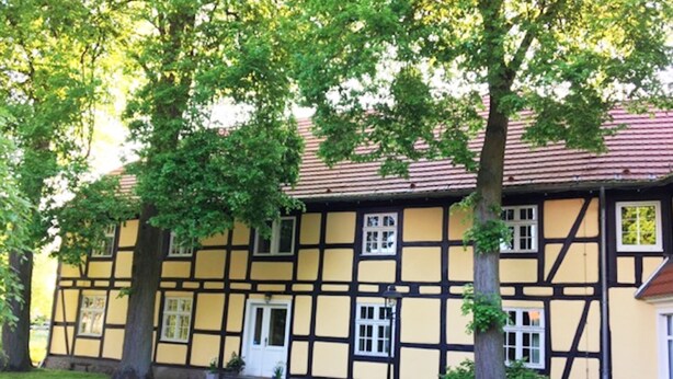 Une maison traditionnelle à colombages, dotée d’un jardin bien entretenu et d’un banc.