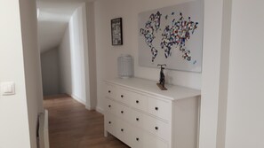 A hallway with a white dresser, a radiator, and a world map artwork on the wall.