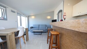 A compact living space with a dining area, a sofa, and a kitchen counter.