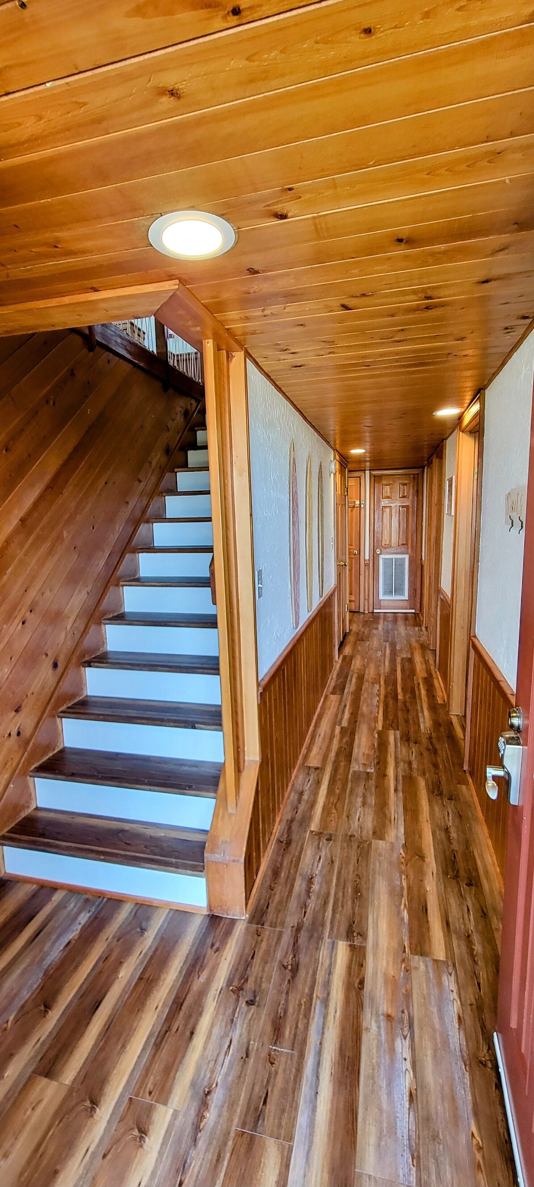 Un interior de madera con una escalera que conduce a una puerta al final.