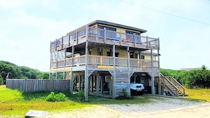 A multi-story building with a balcony, a staircase, and a vehicle parked in front. - WHO IS READY FOR SUNSHINE AND SAND?!  PACK YOUR SENSE OF ADVENTURE & COME VISIT! (Corolla)