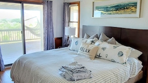 A spacious bedroom with a large bed, a ceiling fan, and a view of the outdoors through a sliding glass door. - WHO IS READY FOR SUNSHINE AND SAND?!  PACK YOUR SENSE OF ADVENTURE & COME VISIT! (Corolla)