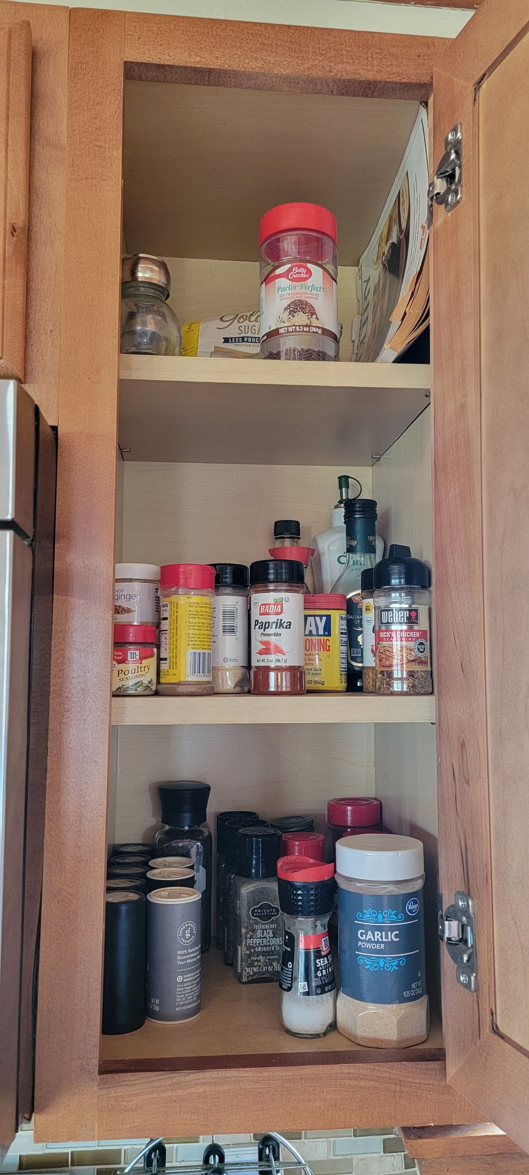 A kitchen cabinet with various spices and condiments, including jars of paprika, pepper, and garlic powder.