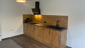 Una cocina moderna con armarios de madera, un lavamanos negro y un lámpara colgante.