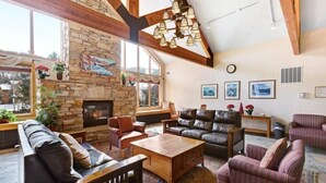 Ein geräumiges Wohnzimmer mit Kamin aus Stein, Ledersofas und einem großen Holztisch.