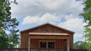Une cabane en bois dotée d’un porche couvert et d’une rambarde en métal.