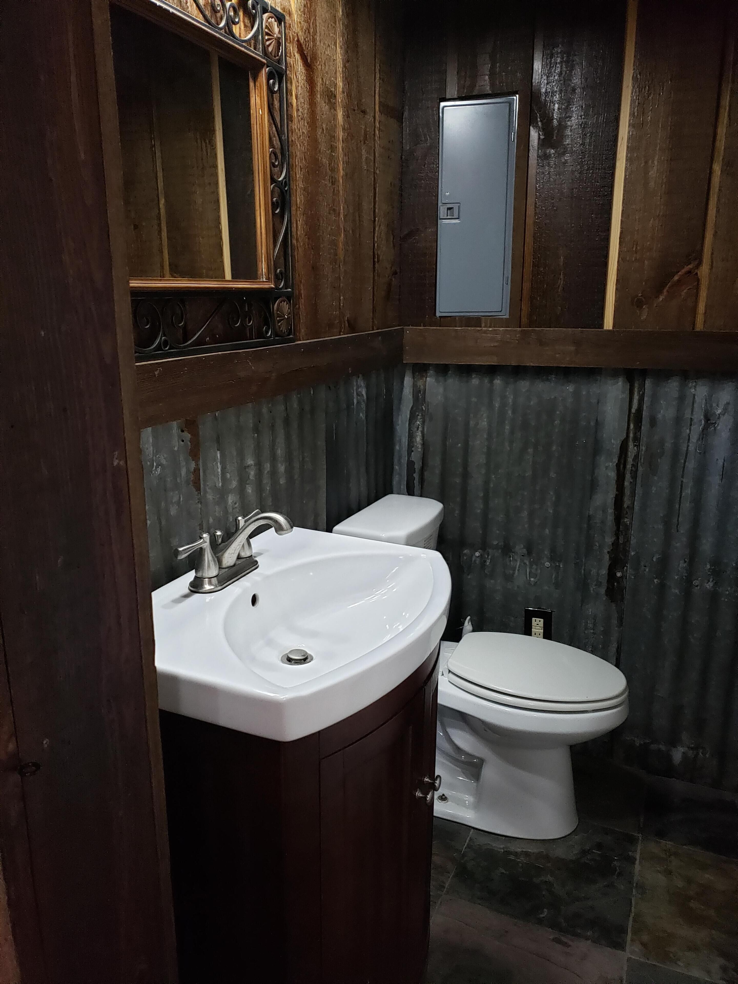 A bathroom with a wooden vanity, a white sink, and a toilet.