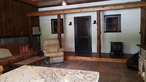 Un salon chaleureux avec un plafond en bois, un canapé en cuir, une table basse en marbre et une porte noire.