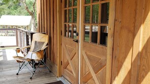 Une véranda en bois dotée d’un espace salon abrité et d’une grande porte en bois avec des panneaux de verre.
