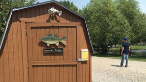 Un abri en bois décoré d’un motif de poisson, avec une pancarte indiquant « Bibliothèque de quartier » et une autre pancarte indiquant « Empruntez un livre ».