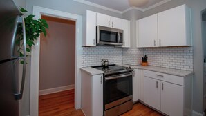 A compact kitchen with white cabinets, a stainless steel refrigerator, a microwave, and an oven. - Luxury on Main / North (Richmond)