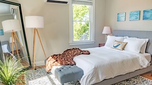 A bedroom with a bed, a bedside table, a lamp, a mirror, and a window. - Luxury on Main / North (Richmond)