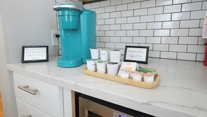 A kitchen with a coffee maker, a tray of coffee cups, and framed thank you signs. - Luxury on Main / North (Richmond)