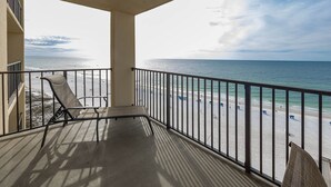 A balcony with a view of a beach, a chair, and a small table. - Lovely Beach Front Condo - Phoenix II Unit 2114 (Orange Beach)