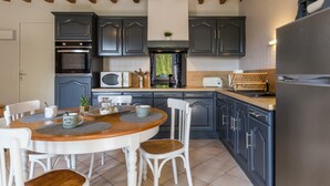 A kitchen with dark cabinets, a wooden ceiling, and a round dining table with chairs.