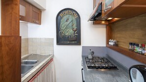 Uma cozinha com armários de madeira, pia de aço inoxidável, fogão a gás e um quadro na parede.
