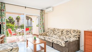 Ein Wohnzimmer mit einer Couch, einem Couchtisch und einem Balkon mit Gartenmöbeln.