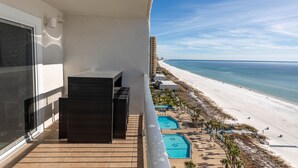 A balcony with a view of a beach and a pool area. - Summit 2BR 2BA 13th Floor End Unit w/ BEACH CHAIRS INCL!!! (Panama City Beach)