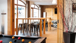 Une salle de billard avec des meubles en bois, une table de billard et de grandes fenêtres.