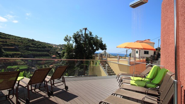 A balcony with sun loungers, a showerhead, and a view of a hillside. - Villas Quinta da Lapa 2. Villa. Heated pool. WiFi (Câmara de Lobos)