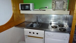A compact kitchenette with a microwave, stove, sink, and dishwasher. - Ski-in/ski-out & foot of the slopes, 17th floor, view resort, tv, 29m², Les Arcs (Les Arcs)