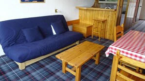 A cozy room with a blue sofa, a wooden table, a checkered tablecloth, and a kitchen area with a microwave. - Ski-in/ski-out & foot of the slopes, 17th floor, view resort, tv, 29m², Les Arcs (Les Arcs)
