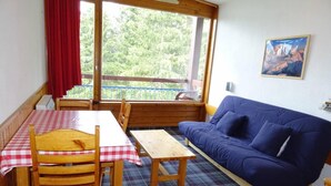 A room with a dining table, chairs, a sofa, and a view through a large window. - Ski-in/ski-out & foot of the slopes, 17th floor, view resort, tv, 29m², Les Arcs (Les Arcs)