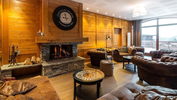 Un salon confortable avec une cheminée, des canapés en cuir et une grande horloge au mur.