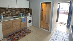 A compact kitchen with a washing machine, a sink, and a tiled backsplash.