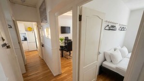 Een modern appartement met houten vloer, een eethoek met tafel en stoelen, een woonkamer met bank en een keuken met koelkast en televisie.