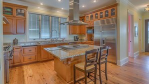 A spacious kitchen with wooden cabinets, a stainless steel range, and a large island with bar stools. - Old Florida, View of St Vincent's Island, Near Boat Landing ~ Island Idyl (Indian Pass)