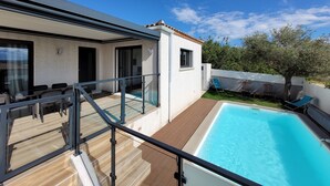 Une maison moderne dotée d’une piscine, d’un patio couvert et offrant une vue sur les environs.