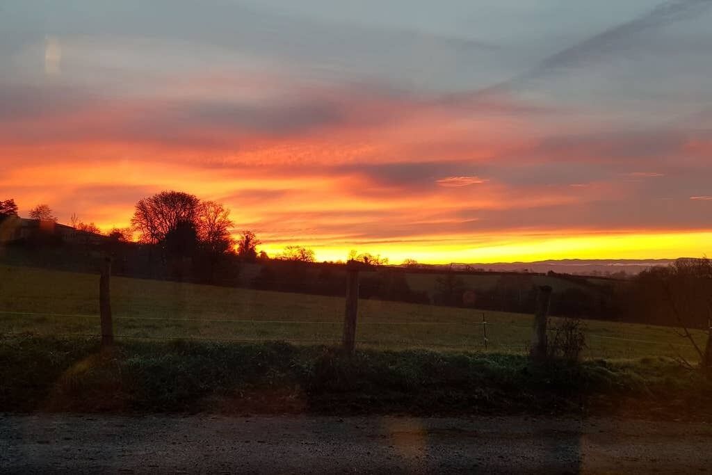 Paisaje rural con una cerca y campos abiertos al atardecer.