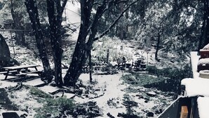 A wooden staircase leading down to a snow-covered garden with benches and a fountain. - NEW: Elegant creekside cabin with waterfall (Idyllwild-Pine Cove)