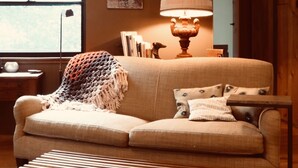 A cozy living room with a sofa, a lamp, a framed picture, and a window. - NEW: Elegant creekside cabin with waterfall (Idyllwild-Pine Cove)