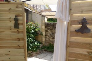 A wooden structure with a stone wall and a small garden area. - Bed and breakfast L'Arlésienne du Mas maurane (Tarascon)