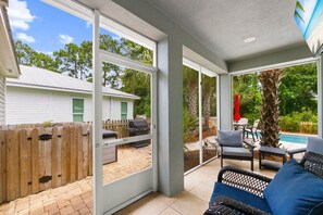 Un patio couvert avec une piscine, du mobilier d’extérieur et une vue sur le jardin.