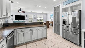 A modern kitchen with white cabinets, a stainless steel refrigerator, and a ceiling fan. - Two Golf Carts ~ Private Pool ~ Screened Porch (Miramar Beach)