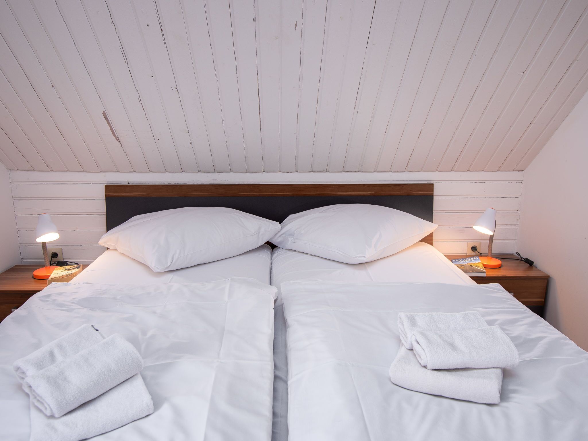 Ein Doppelbett mit weißer Bettwäsche, zwei Kissen und zwei Nachttischlampen.