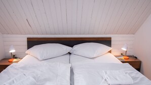 Un lit double avec du linge de lit blanc, deux oreillers et deux lampes de chevet.