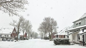 Une rue enneigée, avec des maisons des deux côtés.