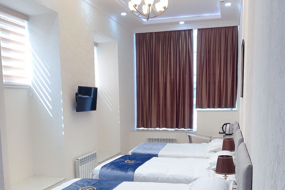 Une chambre d’hôtel avec deux lits, un lustre, un téléviseur à écran plat et une fenêtre avec des rideaux.